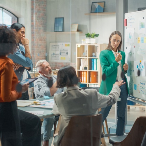 Group of professionals standing and working around a whiteboard