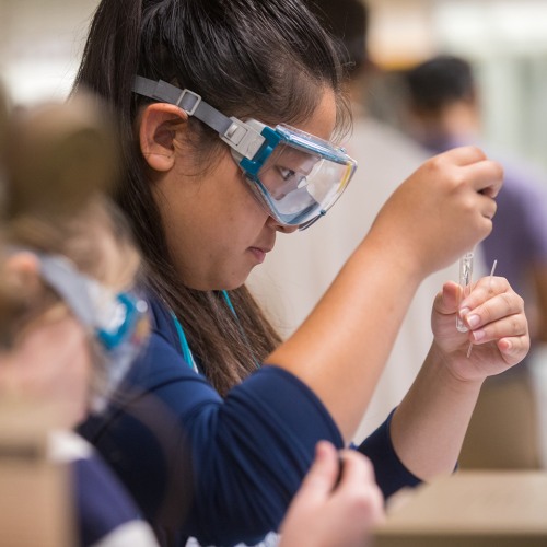 Student studying vial of liquid